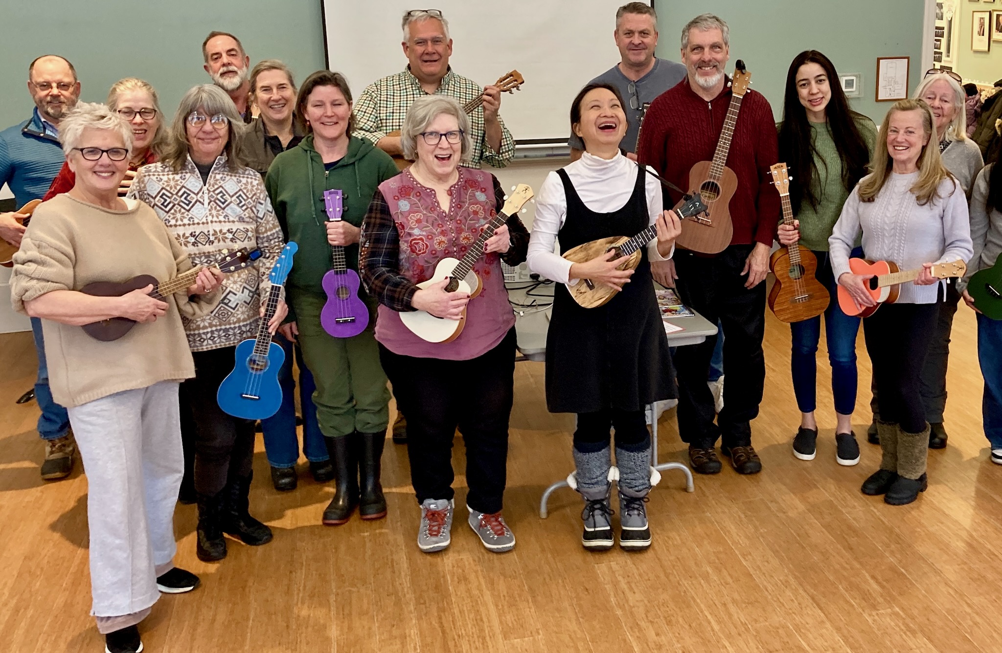 Group of people holding ukuleles and laughing.