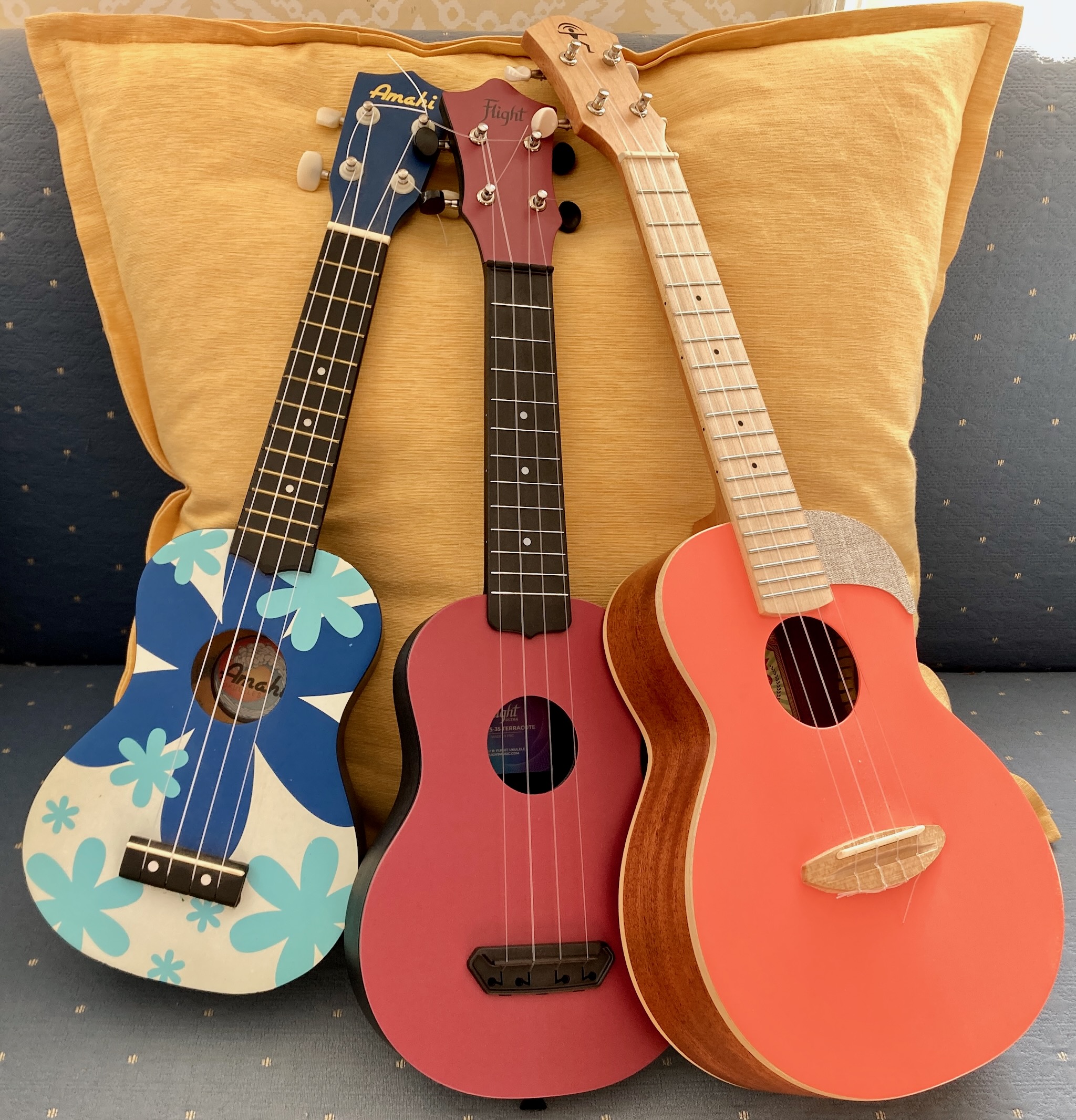 Three brightly colored ukuleles of different sizes and styles.